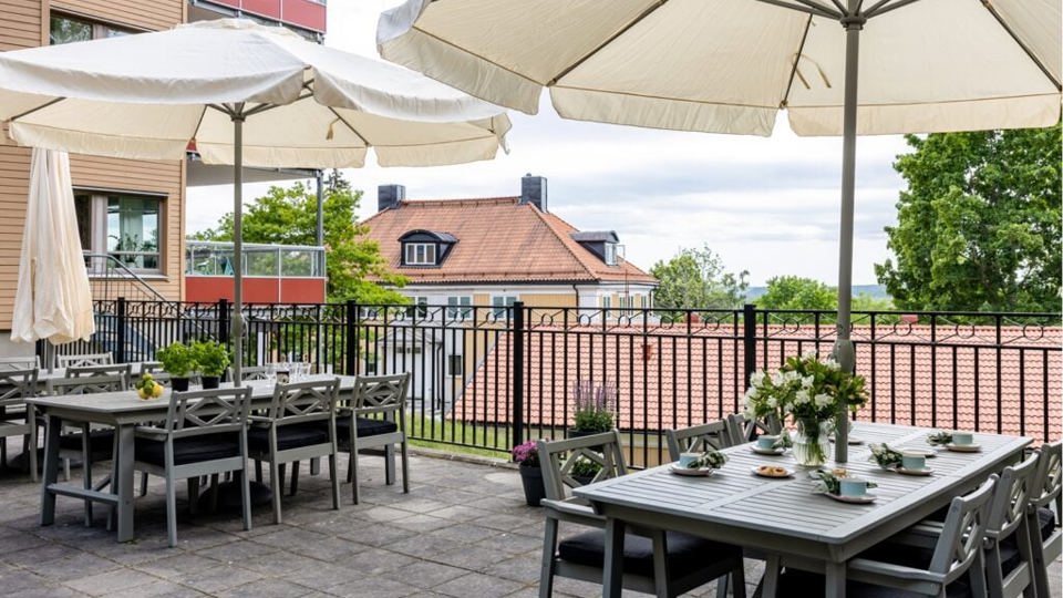 Stenlagd uteplats med dukade bord, vetter mot vattnet.