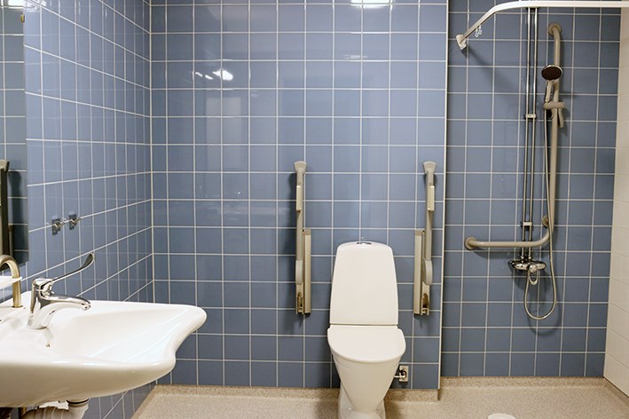 Blått badrum med dusch och toalett