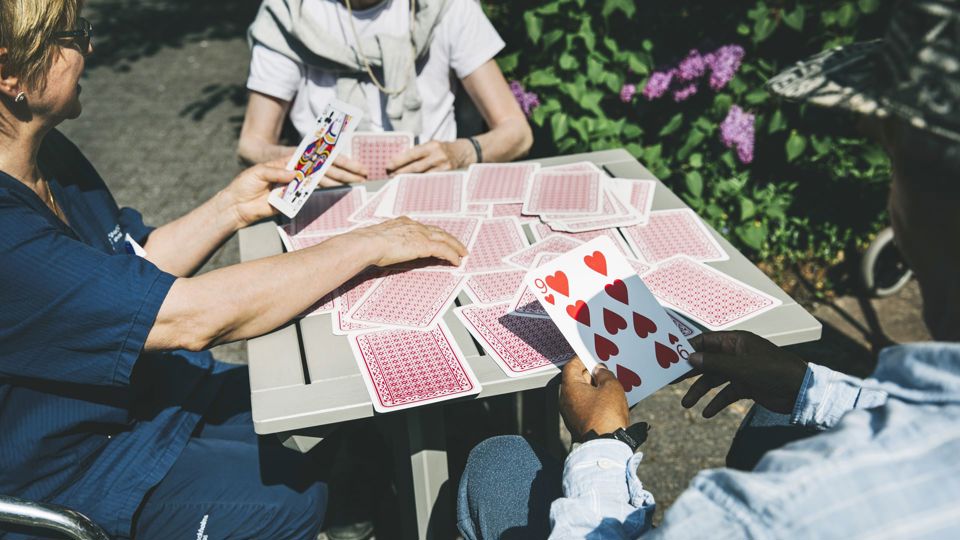 Boende och personal spelar kort på gården.