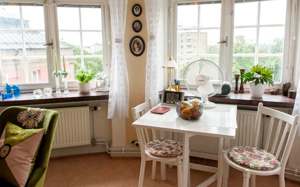 Lägenhet på Guldröllopshemmet. Matbord med stolar, tavlor på väggarna och dekorationer i fönstren.